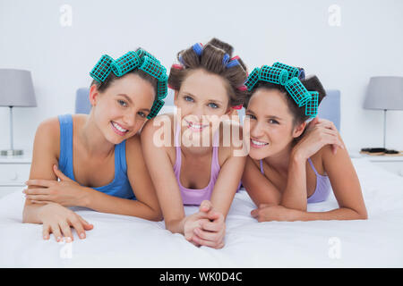 Ragazze in i capelli rulli giacente a letto Foto Stock