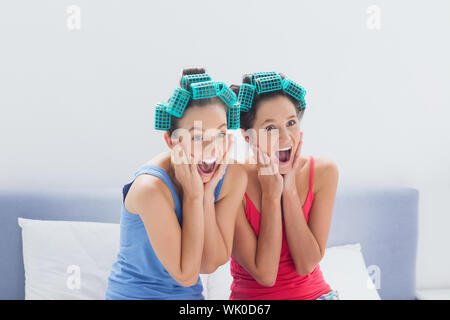 Gli amici con i capelli rulli sulla seduta nel letto Foto Stock