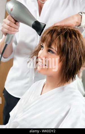 Vista ritagliata del parrucchiere womanÕs di asciugatura dei capelli. Vista laterale Foto Stock