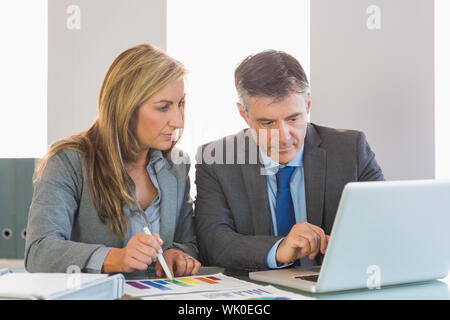 Imprenditore attento che mostra qualcosa sul computer a un attenta imprenditrice Foto Stock