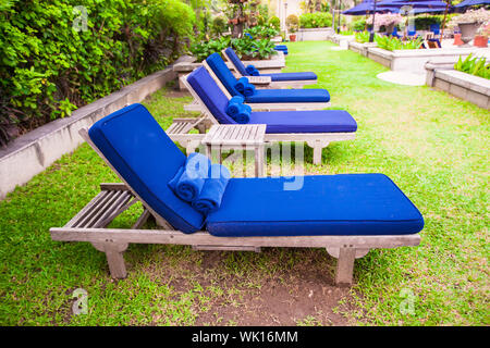 Blue chaise longue vicino alla piscina nel resort di lusso sull'erba verde Foto Stock