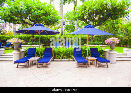 Lettini da spiaggia con ombrelloni vicino alla piscina in hotel di lusso Foto Stock