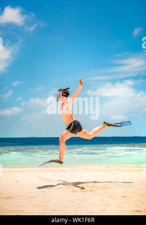 Funny Man jumping in pinne e maschera. Casa vacanze su una spiaggia tropicale a isole delle Maldive. Foto Stock