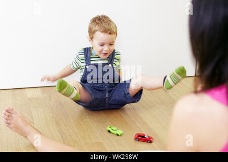Madre e figlio seduti sul pavimento e giocare con modellini di auto. Foto Stock