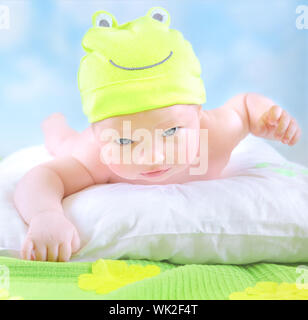 Closeup ritratto di carino piccolo bambino indossando funny frog costume e sdraiarsi a immaginare campo floreale, infanzia felice concetto Foto Stock