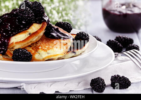 Deliziose frittelle dorate con fresco di more e confettura di more. Estrema profondità di campo. Foto Stock