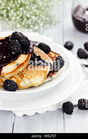 Deliziose frittelle dorate con fresco di more e confettura di more. Estrema profondità di campo. Foto Stock