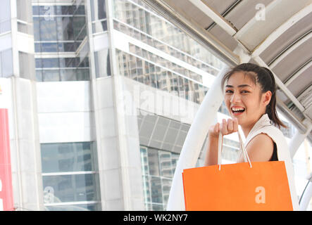 Vista laterale Ritratto di sorridente giovane donna azienda borse per lo Shopping nel ponte di coperta
