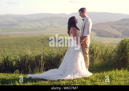 Sposa e lo sposo al di fuori del giardino nozze con African Natal Midlands paesaggio di montagna sullo sfondo Foto Stock