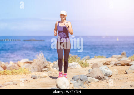 Giovane donna slim in esecuzione vicino al mare al mattino Foto Stock