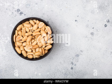 Salate e arachidi tostate classico snack in nero ciotola sul tavolo luminoso.vista superiore Foto Stock