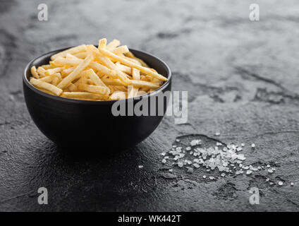 Sale e aceto bastoncini di patate in bianco ciotola, classico snack nero sul tavolo della cucina. Foto Stock