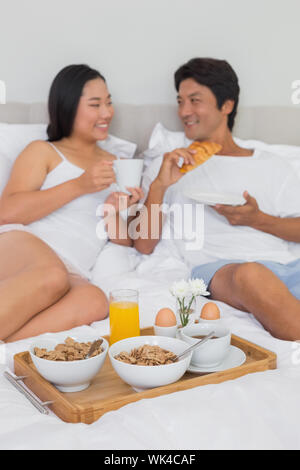 Felice coppia avente la colazione a letto a casa in camera da letto Foto Stock