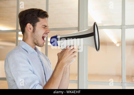 Imprenditore Casual urlando attraverso il megafono nel suo ufficio Foto Stock