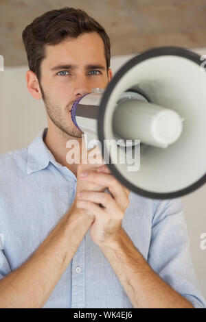 Casual uomo d affari di parlare attraverso il megafono nel suo ufficio Foto Stock