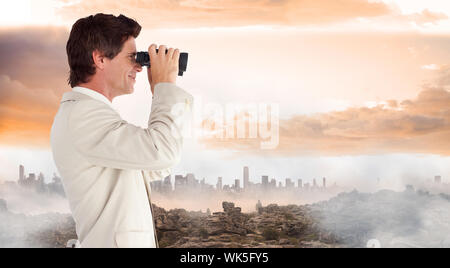 Imprenditore utilizzando il binocolo contro brumoso paesaggio Foto Stock