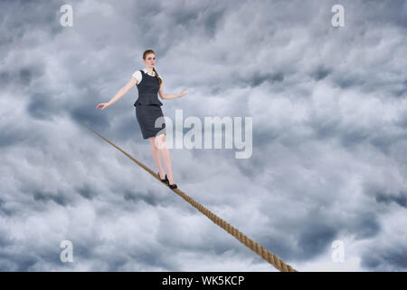 Immagine composita di imprenditrice facendo un bilanciamento atto contro il cielo nuvoloso Foto Stock