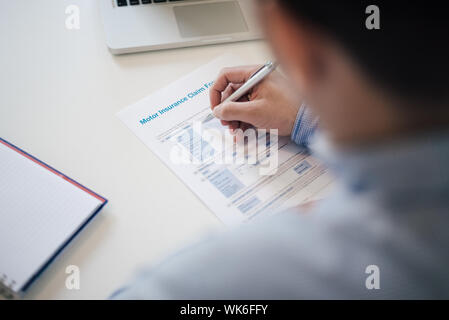 Man mano di contenimento riempimento motore auto insurance claim form imprenditore maschio riempie la rivendicazione di trasporto rappresentante di rischio società di assicurazioni investiga Foto Stock