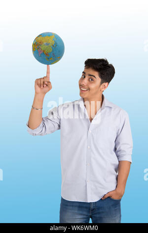 Giovane uomo che gira un globo a portata di mano Foto Stock