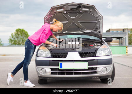 Donna ispezione broken auto motore. Foto Stock