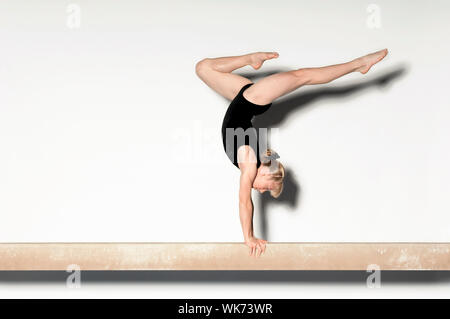 Giovani facendo ginnasta Handstand sul fascio di equilibrio Foto Stock