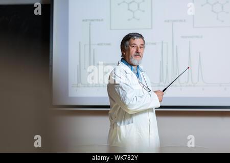 Senior professore di chimica dando una lezione nella parte anteriore dell'aula piena di studenti (SHALLOW DOF; dai toni di colore immagine) Foto Stock