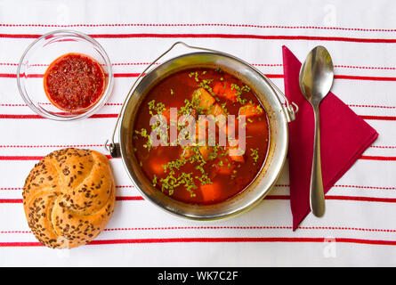 Gulasch ungherese la zuppa in un piccolo gulasch di metallo-kettle servito. Foto Stock