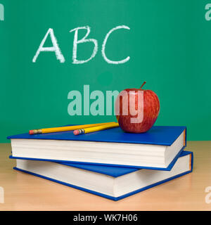 ABC scritto su una lavagna. Libri, matite e un apple sul primo piano. Foto Stock