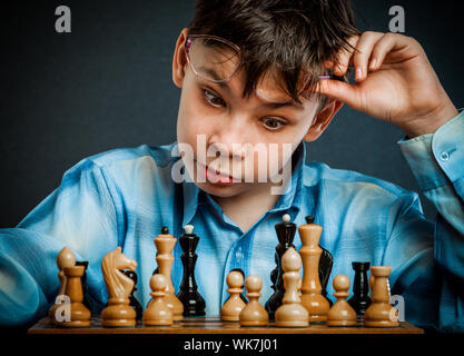 Wunderkind giocare a scacchi. Funny Nerd Ragazzo. Foto Stock