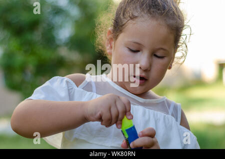 Carino bambina cercando curiosamente presso il giocattolo sulla sua mano. Foto Stock