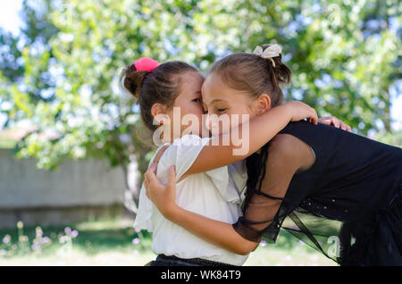 Due graziosi sorelle stanno abbracciando ogni altro all'esterno. Foto Stock