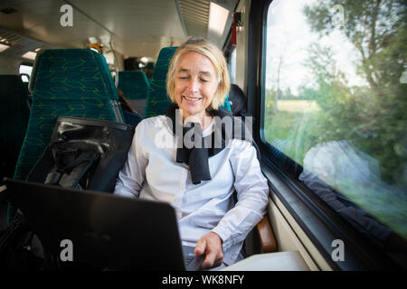 Cottbus, Germania. 20 agosto 2019. Christiane Hipp, facente funzione di presidente del Land di Brandeburgo l'Università Tecnica di Cottbus, siede in treno regionale e lavora sui notebook. Hipp commuta ogni giorno da Berlino al suo posto di lavoro. Credito: Arne Immanuel Bänsch/dpa/Alamy Live News Foto Stock