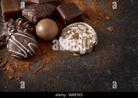 Cioccolata, biscotti e praline al buio su un sfondo di ardesia con spazio di copia Foto Stock