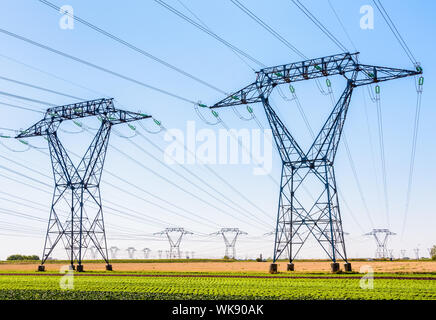 Decine di piloni di elettricità nella campagna francese sotto un cielo blu chiaro. Foto Stock