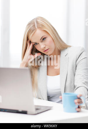 Immagine interna di annoiato e stanco della donna con il computer portatile Foto Stock