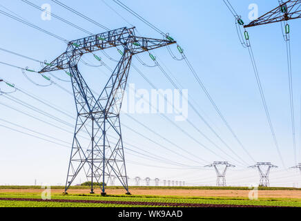Decine di piloni di elettricità nella campagna francese sotto un cielo blu chiaro. Foto Stock