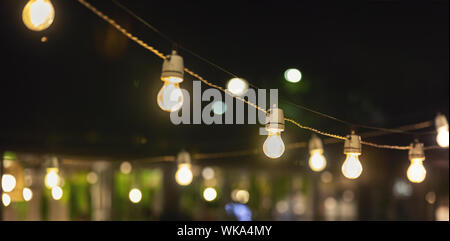 Festa delle luci di stringa appesa sopra il ristorante sulla terrazza all'aperto Foto Stock