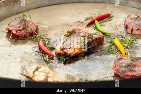 Porzioni di assortimento materie bistecca con t-osso, controfiletto e filetto guarnita con erbe fresche e peperoncino piccante pronta per la cottura su piastra Foto Stock