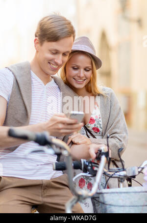 Vacanze estive, biciclette, amore, relazione, navigazione gps e concetto di dating - giovane con le biciclette e lo smartphone nella città Foto Stock