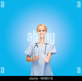 Salute, medicina e farmacia concetto - sorridente medico o infermiere con uno stetoscopio offrendo pillole e bicchiere di acqua Foto Stock