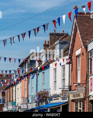 Classic estate English street con vivacemente colorati negozi e case con bunting infilate al di là della strada. Foto Stock