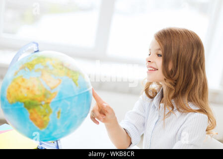 L'istruzione e il concetto di scuola - smilng poco ragazza dello studente con globo a scuola Foto Stock