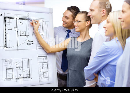 Business, costruzione, creazione e il concetto di ufficio - sorridente team aziendale blueprint di disegno sul flip board e avente la discussione Foto Stock