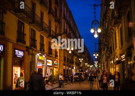 Barcelona, Spagna - 2019. La gente che camminava sulle vecchie strade di Barcellona di notte tra negozi locali e bar di tapas. Foto Stock