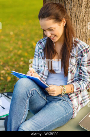 Sorridente adolescente iscritto nel notebook Foto Stock
