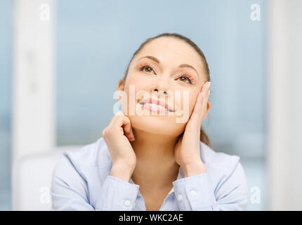 Sorridente imprenditrice di sognare in ufficio Foto Stock