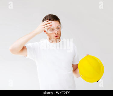 Costruzione, sviluppo, costruzione e il concetto di architettura - Foto di maschio builder in occhiali di sicurezza tenendo off Casco giallo Foto Stock
