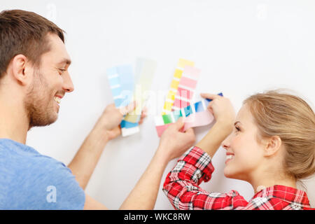 Riparazione, interior design, costruzione, rinnovo e home concetto - sorridente giovane guardando i campioni di colore sono a casa Foto Stock