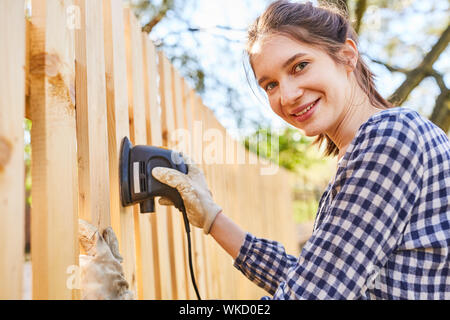 Giovane donna come un tuttofare o artigiano apprendista presso il recinto macinare in giardino Foto Stock