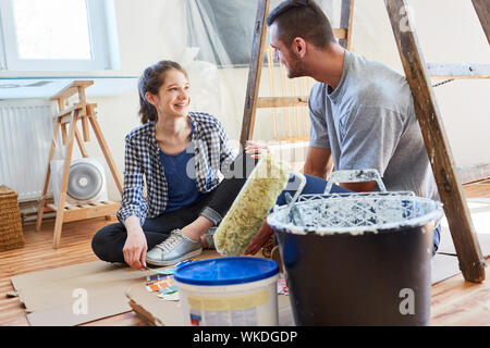 Felice coppia giovane come un miglioramento di casa rompere nella nuova casa mentre il rinnovamento Foto Stock